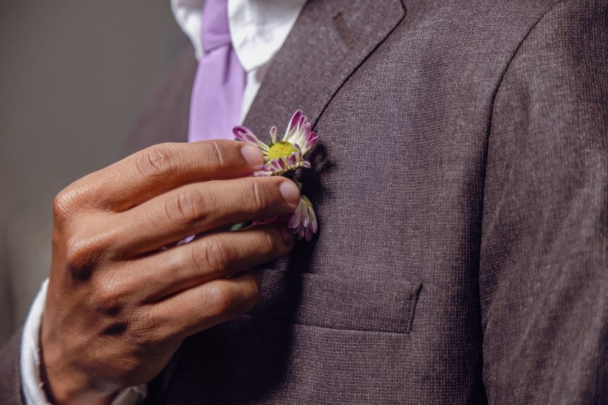 A groom adjusting a boutonniere