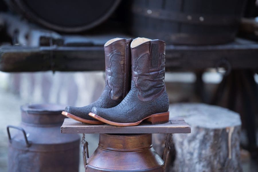 Worn brown leather western boots on a sidewalk