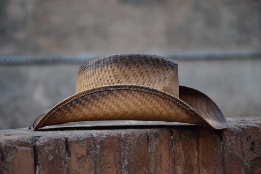 A straw cowboy hat against a brick wall